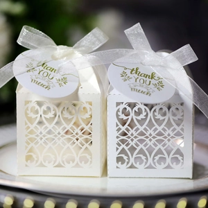 Detail of laser-cut hollow candy box with ivory vine patterns and thank you gift tags