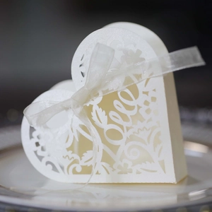 Close-up of pearl white laser-cut heart favor box with LOVE text and ribbon bow detail