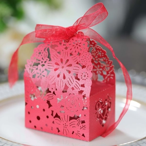 Detail of red laser-cut candy box with intricate floral patterns and organza ribbon bow