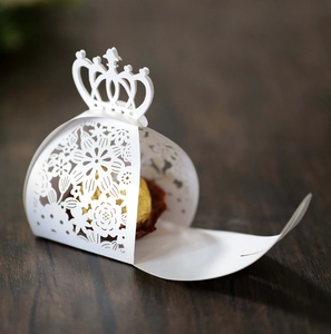 Close-up of white laser-cut crown candy box with elegant floral cutout and chocolate