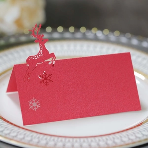 Detail of red Christmas place card with laser-cut reindeer and snowflake on dinner plate