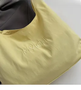 Detailed view of MVICHI logo embroidery on soft light green nylon tote bag surface