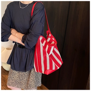 Close-up of red and white striped mesh tote bag with durable leather trim on shoulder