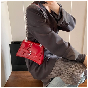 Detail of red glossy leather shoulder bag with silver chain strap and buckle decor