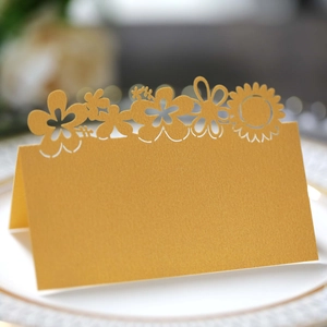 Detail of laser-cut golden sun flower place card on an elegant white dinner plate