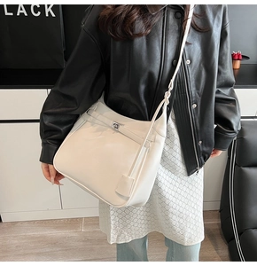 Minimalist beige leather tote bag with metal buckle detail and adjustable strap