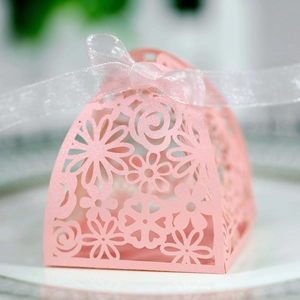 Detail of pink laser-cut wedding favor box with pearl paper and white ribbon bow
