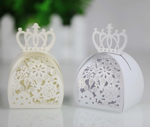 Detail of laser-cut crown handle gift boxes with intricate floral patterns for weddings