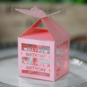 Pink laser cut Happy Birthday candy box with butterfly and heart cutouts on a plate