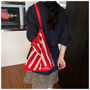 Détail d'un sac cabas en maille à rayures rouges et blanches porté par un mannequin