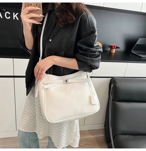 Close-up of a white leather bucket bag with silver metal twist lock and thin shoulder strap