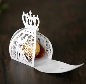 Detail of white laser-cut wedding candy box with Mr & Mrs crown design and chocolate inside