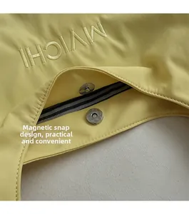 Detail of magnetic buckle closure and embroidered logo on striped fabric tote bag