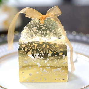 Detail of laser-cut golden floral candy box featuring a sheer organza ribbon bow