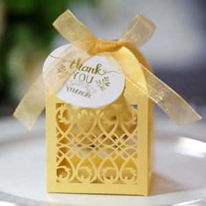 Close-up of laser-cut gold candy box with delicate patterns, ribbon and thank you tag