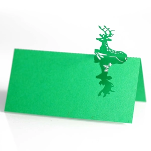 Close-up of green laser-cut place card with reindeer and snowflake details for holiday tables