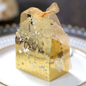 Macro view of gold laser-cut candy box with intricate floral patterns and organza ribbon