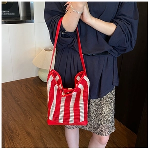 Détail d'un sac cabas en filet à rayures rouges et blanches porté par une personne chez soi