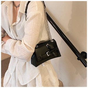 Close-up of black crossbody bag with silver hardware and chain strap on a model