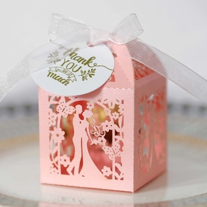 Macro detail of laser-cut pink wedding favor box with bride silhouette and thank you tag