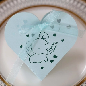Dettaglio scatola regalo a cuore azzurra in carta con elefante e fiocco di nastro