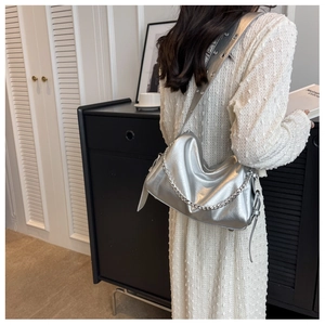 Detail of silver metallic pleated shoulder bag with chunky chain and wide eyelet strap