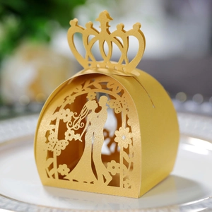 Close-up of golden laser-cut wedding favor box with bride groom silhouette and crown