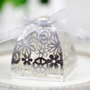 Macro view of laser-cut silver candy box with intricate floral patterns and silk ribbon