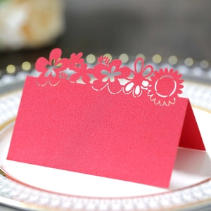 Macro shot of red laser-cut floral place card on elegant white porcelain plate