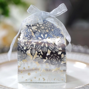 Macro view of laser-cut floral pattern on silver candy box with elegant ribbon bow