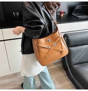 Brown leather tote bag featuring a silver twist lock and crossbody strap on a model