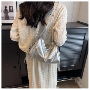 Detail view of metallic silver crossbody bag with eyelet wide strap and chain accent