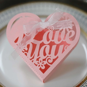 Detail of pink heart-shaped laser cut favor box with Love You text and white ribbon bow