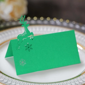 Detail of green laser-cut reindeer and snowflake place card on elegant plate