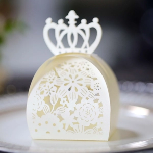 Macro shot of laser-cut cream wedding favor box with crown handle and floral patterns