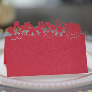 Detail of red hollowed-out sunflower laser-cut wedding place card on white ceramic plate