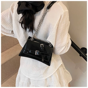 Detail of a chic black patent leather crossbody bag with bold silver metal chain strap
