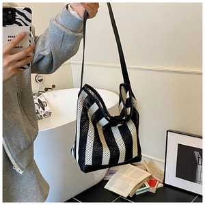 Détail du sac seau en maille rayée avec base en cuir et bandoulière en décor décontracté
