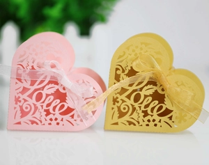 Detail of heart-shaped laser cut wedding favors in pink and gold with ribbon bow