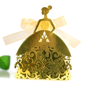 Macro detail of laser-cut floral pattern on golden wedding favors box with silk bow