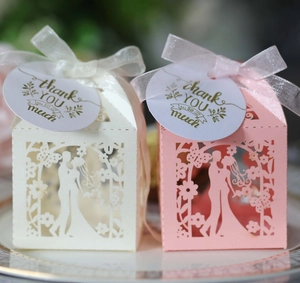 Close-up of laser-cut wedding favor box with ivory ribbon and golden thank you tag