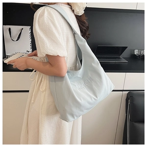 Detail of light blue hobo tote bag featuring 3D MVICHII embroidery and wide shoulder strap