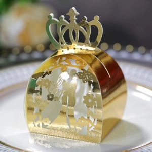 Macro view of gold laser-cut wedding candy box with bride and groom silhouette crown