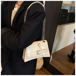 Detail of creamy white crossbody bag with silver buckles and polished leather texture