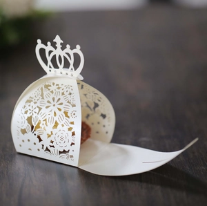 Detailed laser cut white cardstock candy box with elegant crown handle and floral pattern