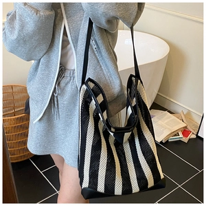 Détail d'un grand sac cabas en filet rayé noir et blanc avec coins en cuir renforcés