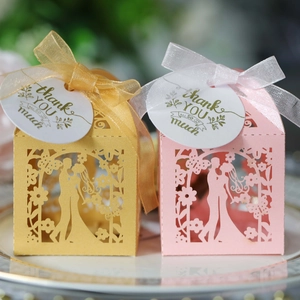 Detail of laser-cut wedding favor boxes with bride and groom silhouette and satin ribbons