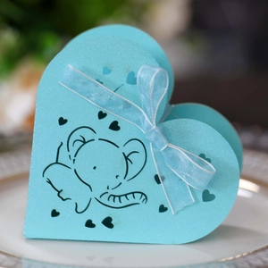 Scatola di caramelle azzurra a forma di cuore con elefante e nastro su piatto bianco