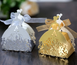 Detailed laser-cut bridal dress favor boxes in gold and white with ribbon bows