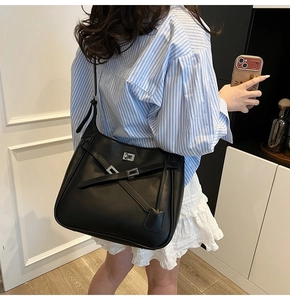 Detail of black matte leather tote bag featuring crisscross straps and silver metal buckle